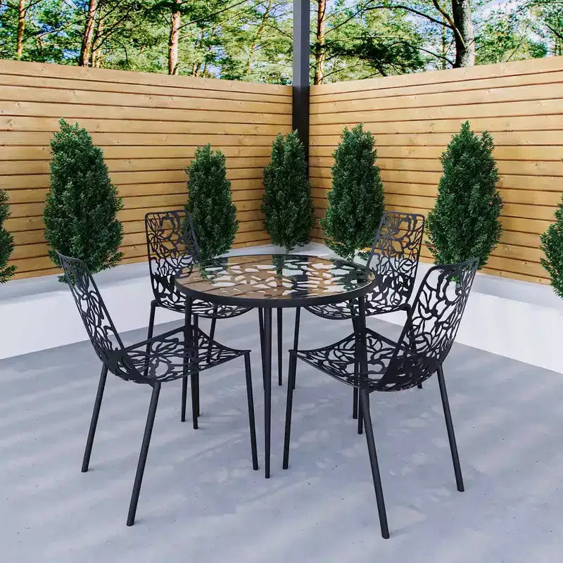 LeisureMod Devon 5-Piece Outdoor Dining Set - Round Glass Table with 4 Black Flower Design Stackable Chairs